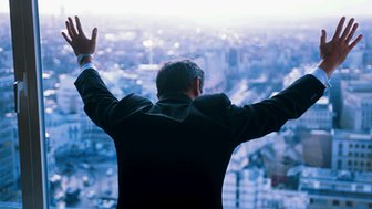 A man stands with his hands on a window pane